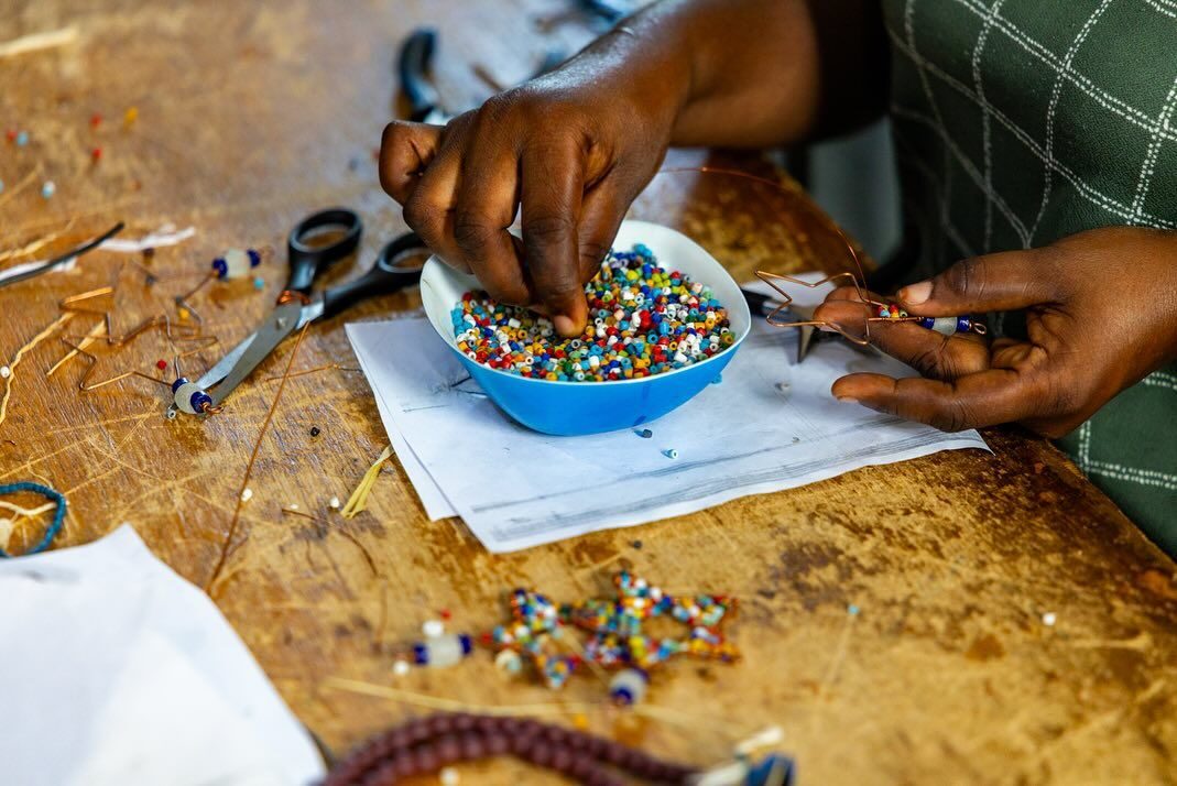 Hands sorting colourful recycled-glass beads in a bowl at a bead-making class in Accra