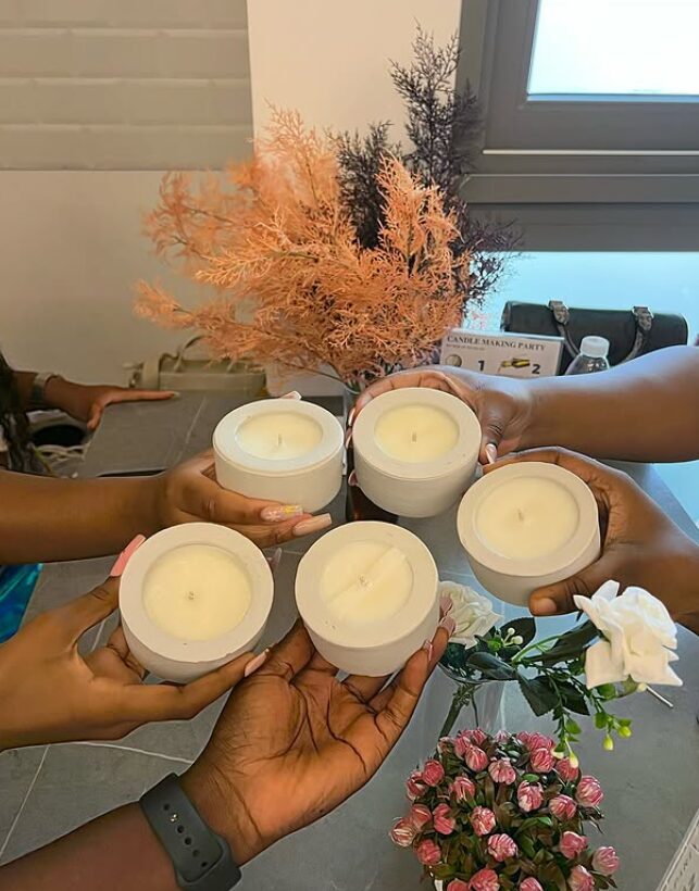 Guests holding up the scented candles they poured at a workshop in Accra