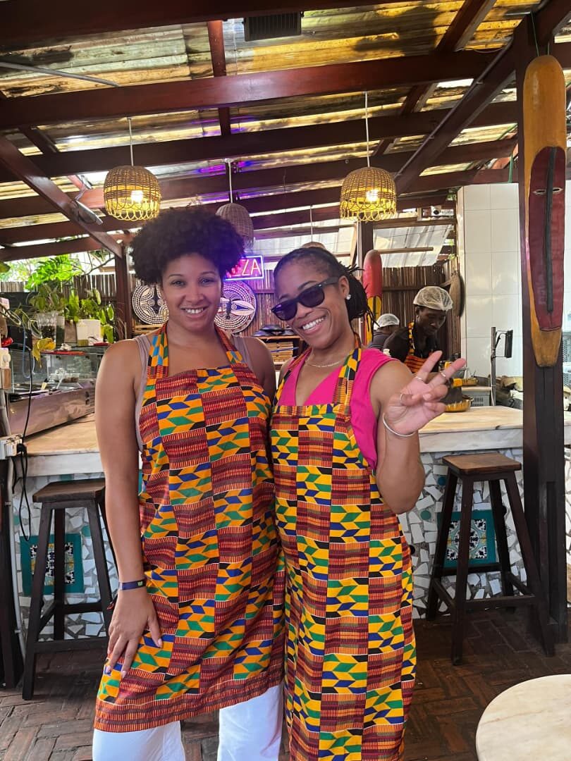 Two happy guests in kente aprons at a Ghanaian cooking class in Accra
