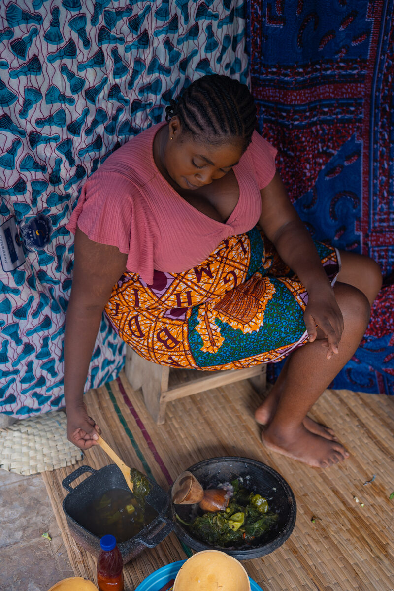 Cooking a Ghanaian dish in a pot over a traditional coalpot