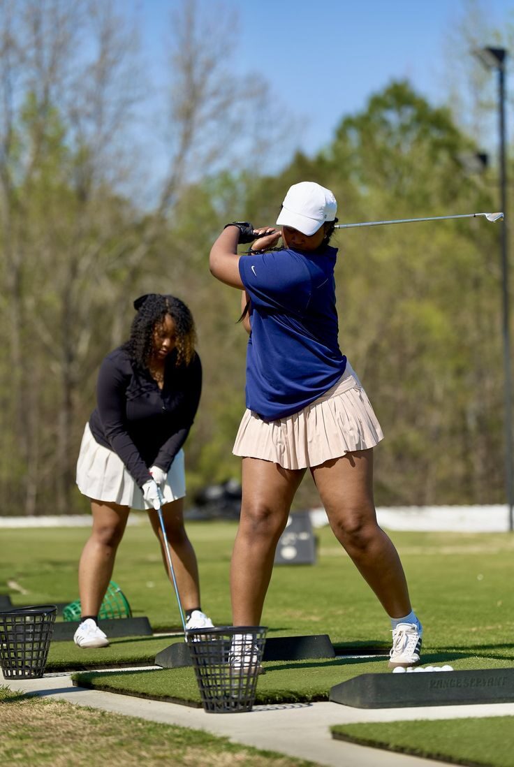 Two women practising at a golf driving range in Accra