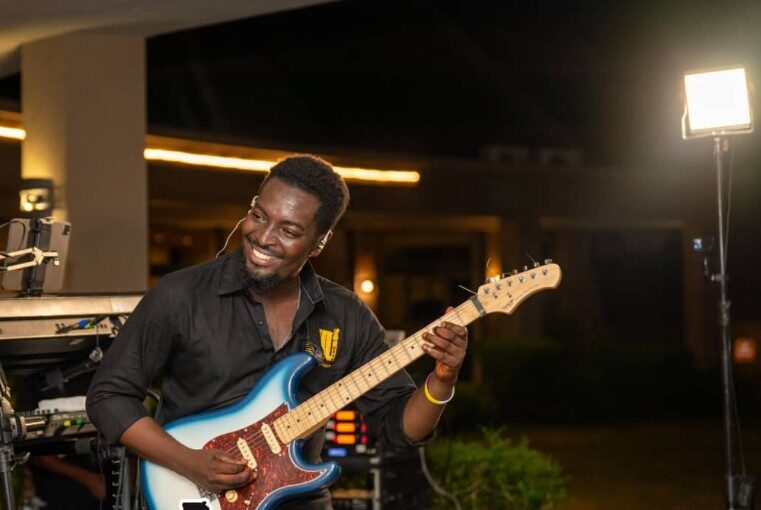 A guitarist performing on stage at night in Accra