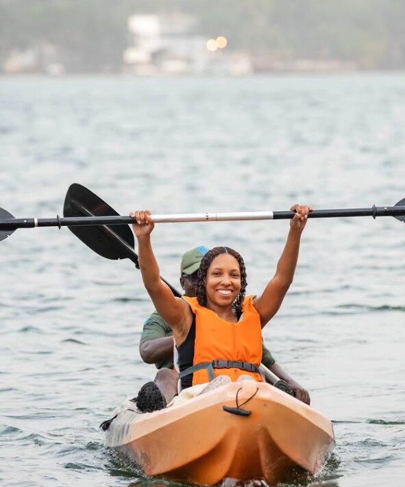 A guest raising a paddle while kayaking on the Volta Lake in Ghana