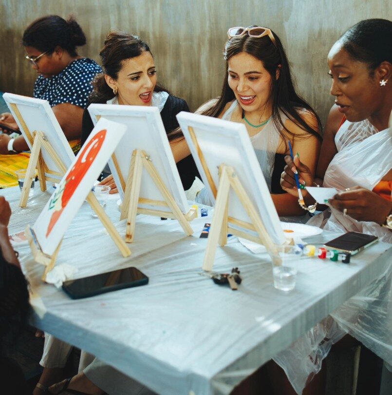 A group painting at easels with drinks at a paint and sip session in Accra