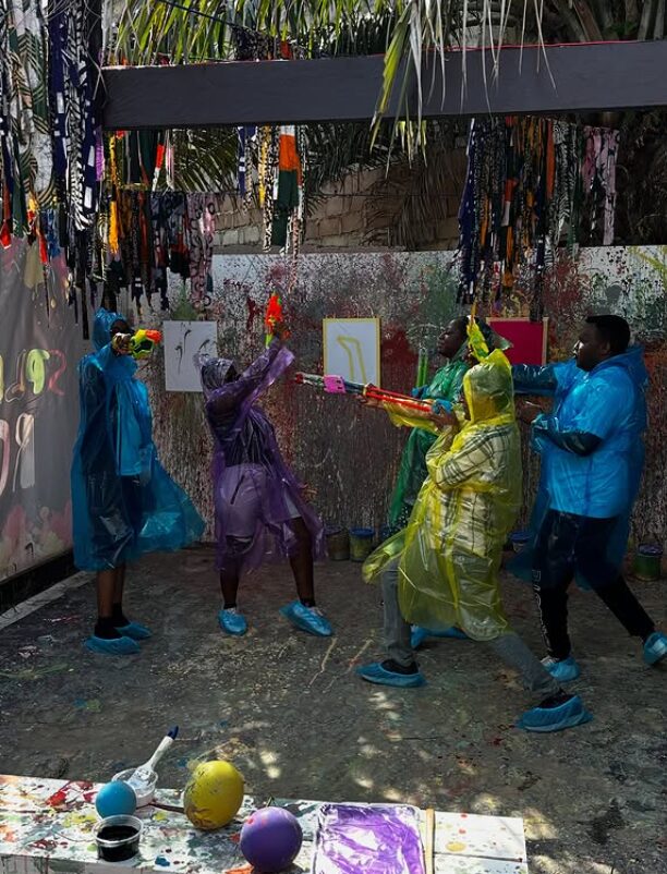 Guests in ponchos throwing paint at a splatter-painting session in Accra