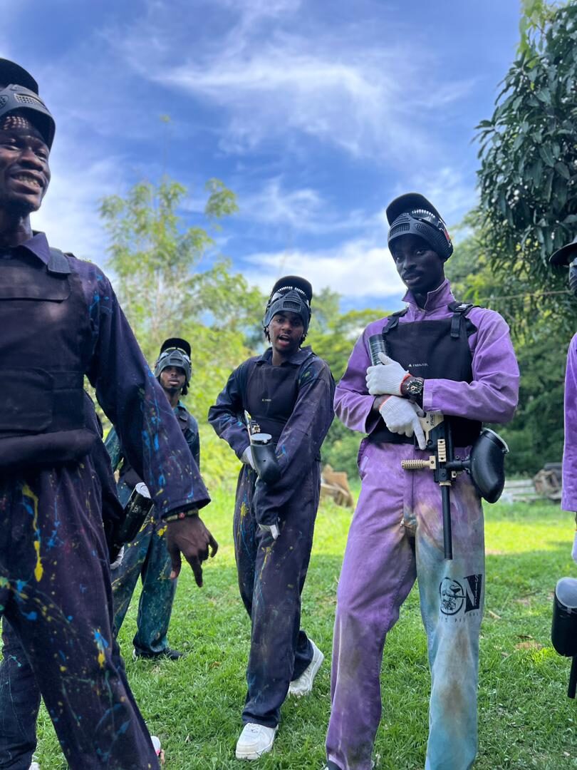 Two guests in paint-splattered paintball suits near Accra