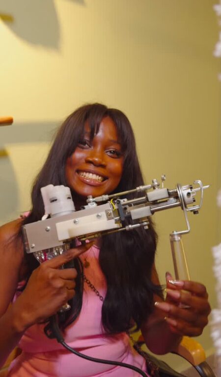 A smiling guest holding a tufting gun at a rug-tufting workshop in Accra